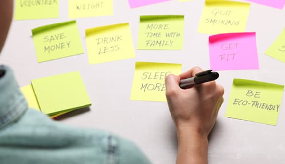 A person writing resolutions on sticky notes
