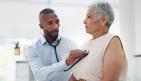 A cardiologist listening to a woman's heart