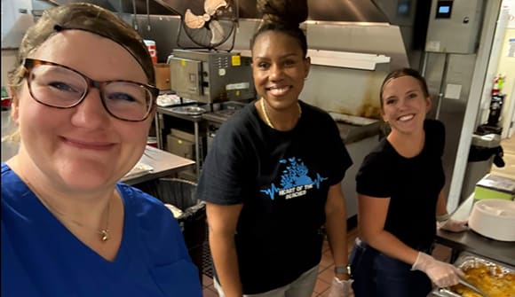 smiling volunteers in a kitchen serving food