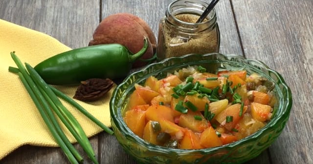 a bowl of peach chutney and ingredients on a table