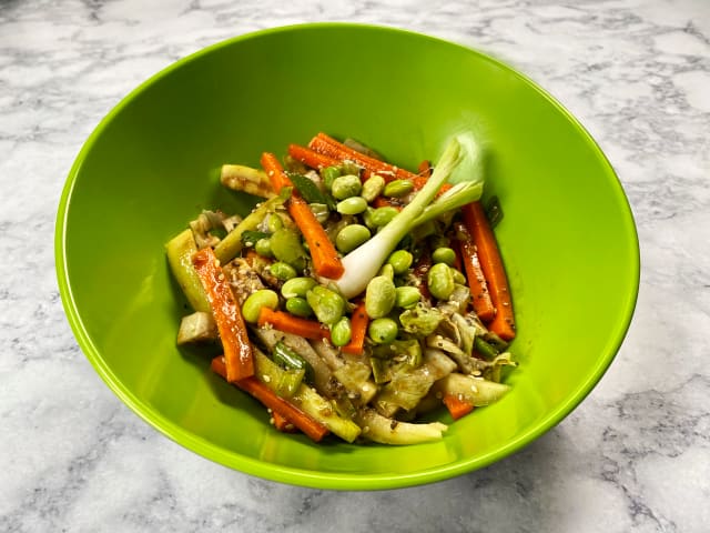 a small lime green bowl filled with pad Thai sitting on a marble countertop