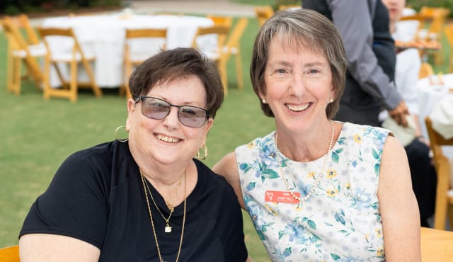 2 smiling woman sitting together outside