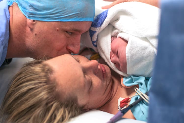 a husband and wife hold their newborn baby boy for the first time.