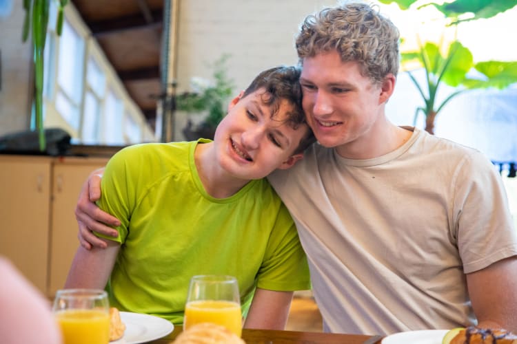 A boy with autism hugs his brother at breakfast