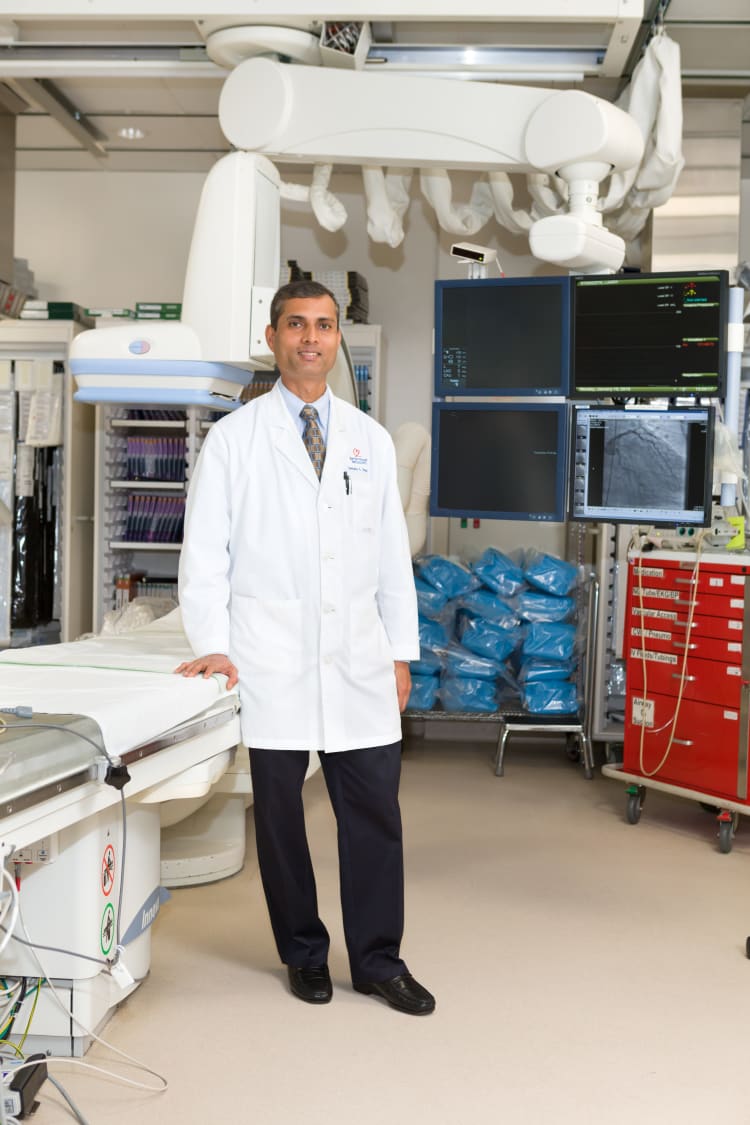 photo of Venkata Sagi, MD, FHRS, clinical cardiac electrophysiologist with Baptist Heart Specialists, standing next to an operating table