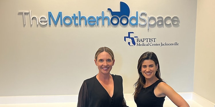 Smiling women standing in front of The Motherhood Space sign