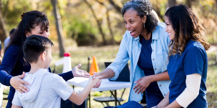 Boy shakes hands with volunteer while his mother pats him on the back