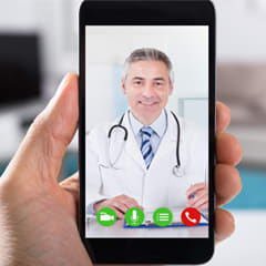 photo of a hand holding a smart phone with a doctor on the screen