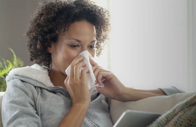 woman sneezing into tissue