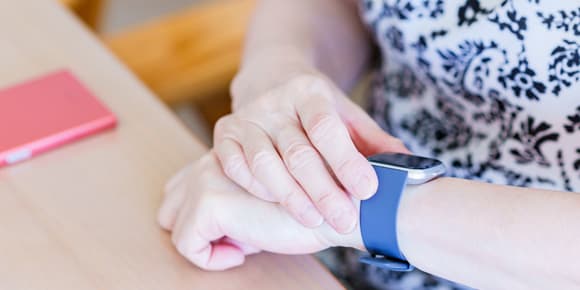 close up of a woman adjusting the blue smart watch on her wrist