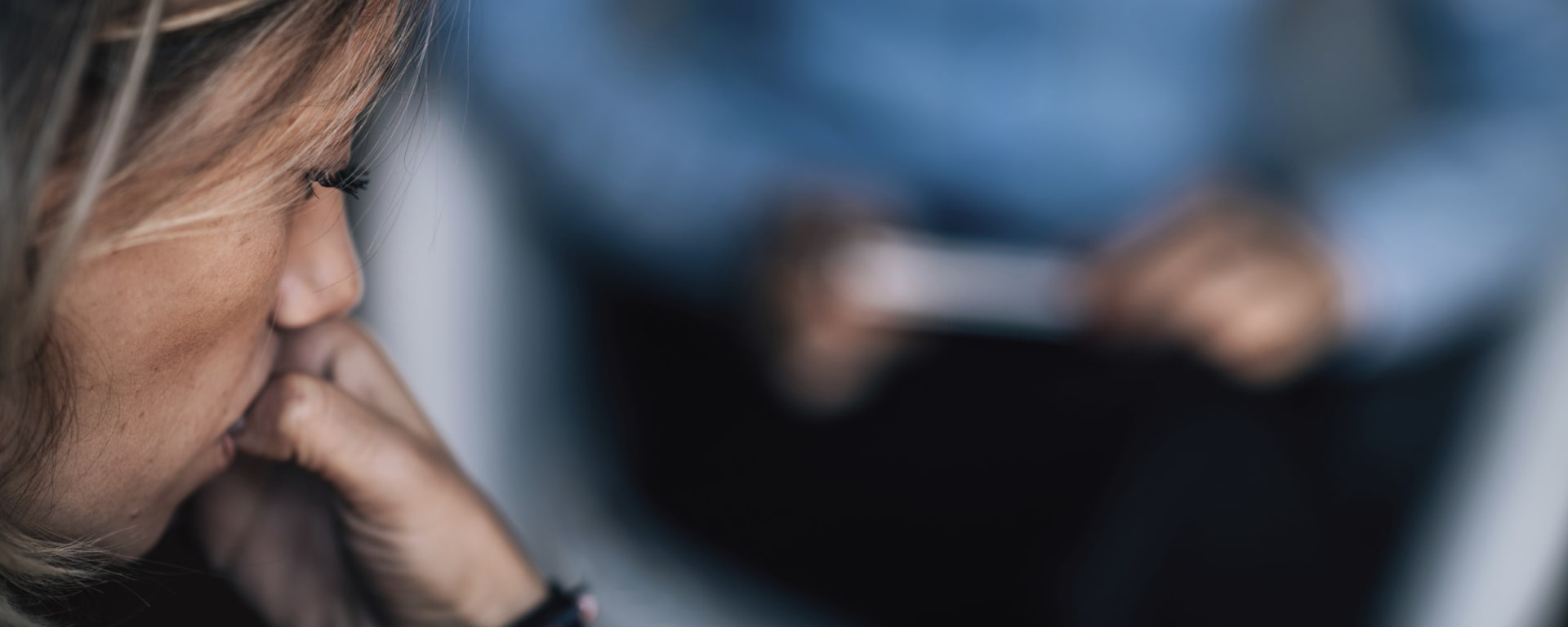 side of a woman's face as she's biting her nails while talking to a mental health counselor