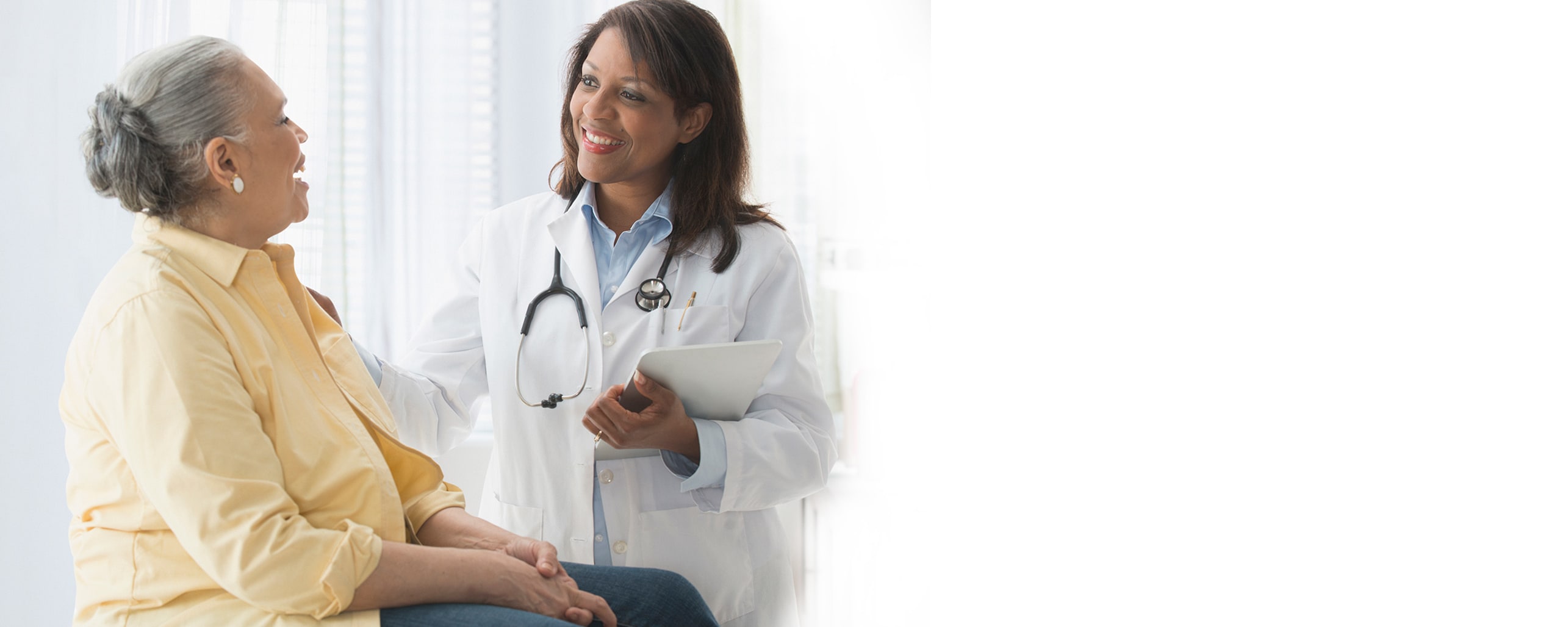 smiling female doctor resting her hand on the shoulder of a laughing female patient