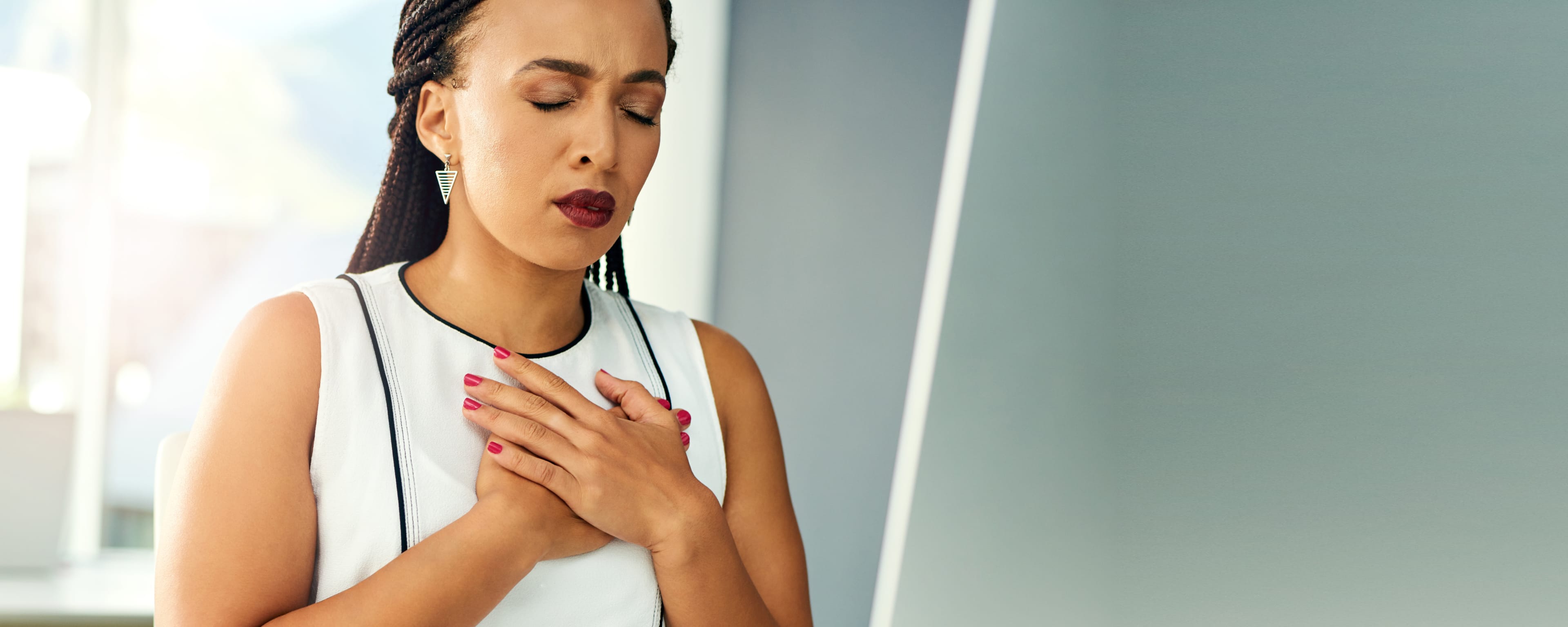 woman with hands on chest experiencing heartburn