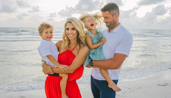 Patient Sara Walsh with her husband and their two kids standing on the beach