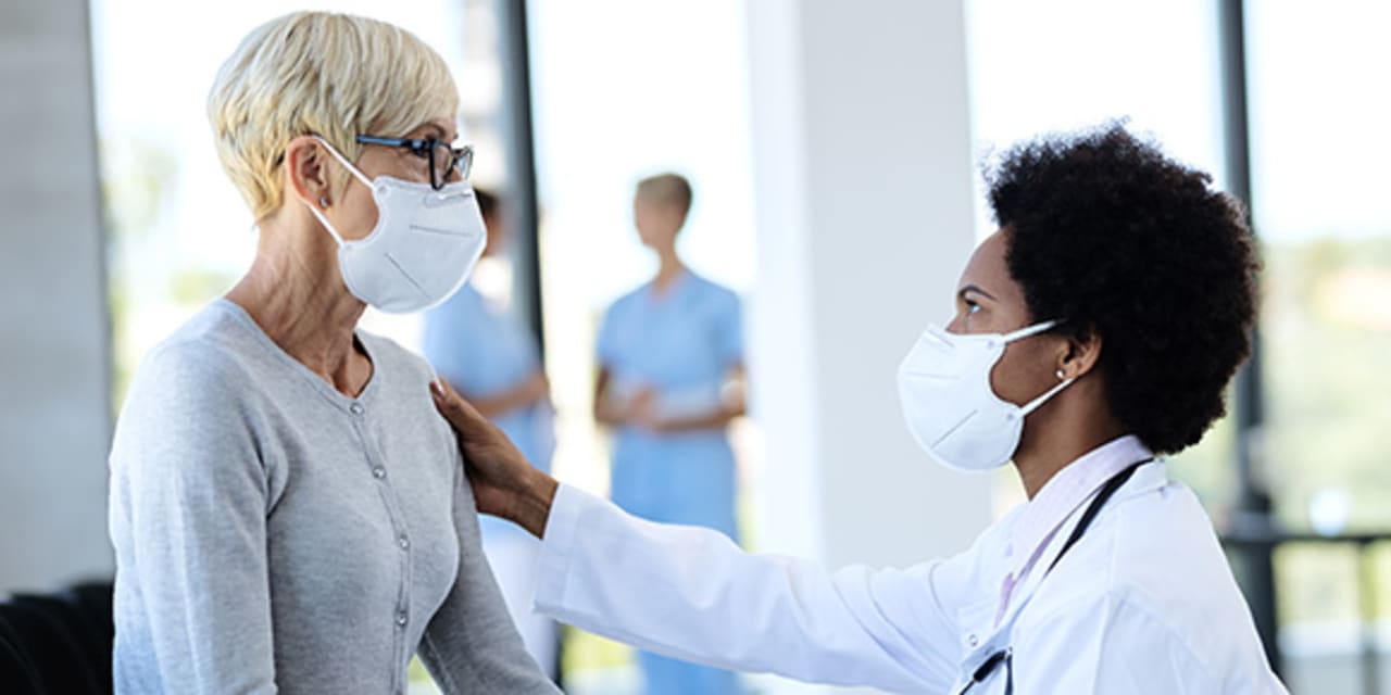 A physician and patient are sitting down looking at one another in a hospital lobby. 