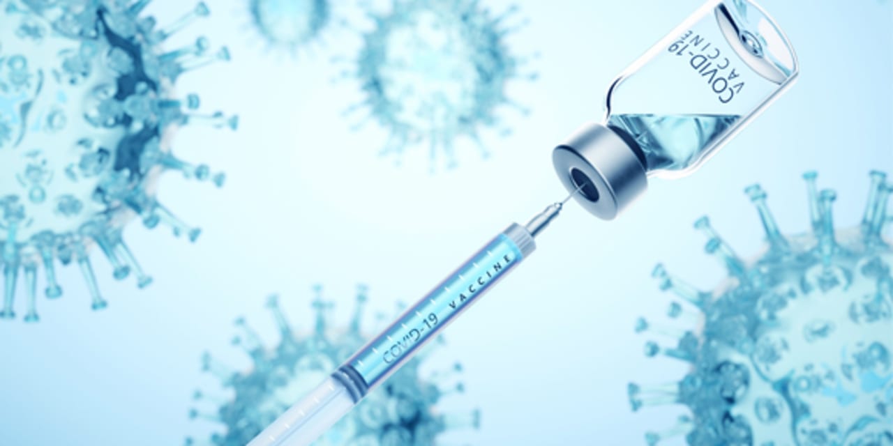 Photograph of a needle entering a bottle filled with fluid. The picture represents a new vaccine, with the needle enterering the glass bottle. 