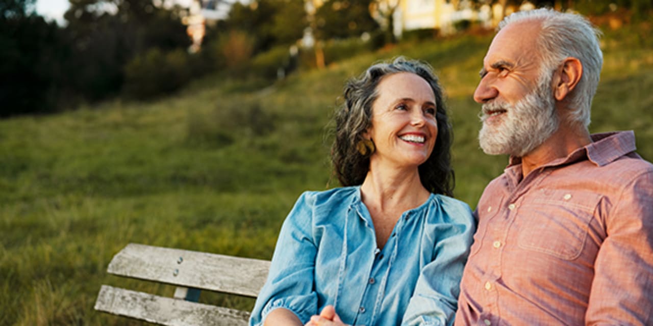 A senior couple happy and sitting on a park bench together