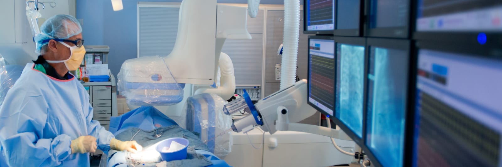 surgeon operating on patient in front of multiple screens