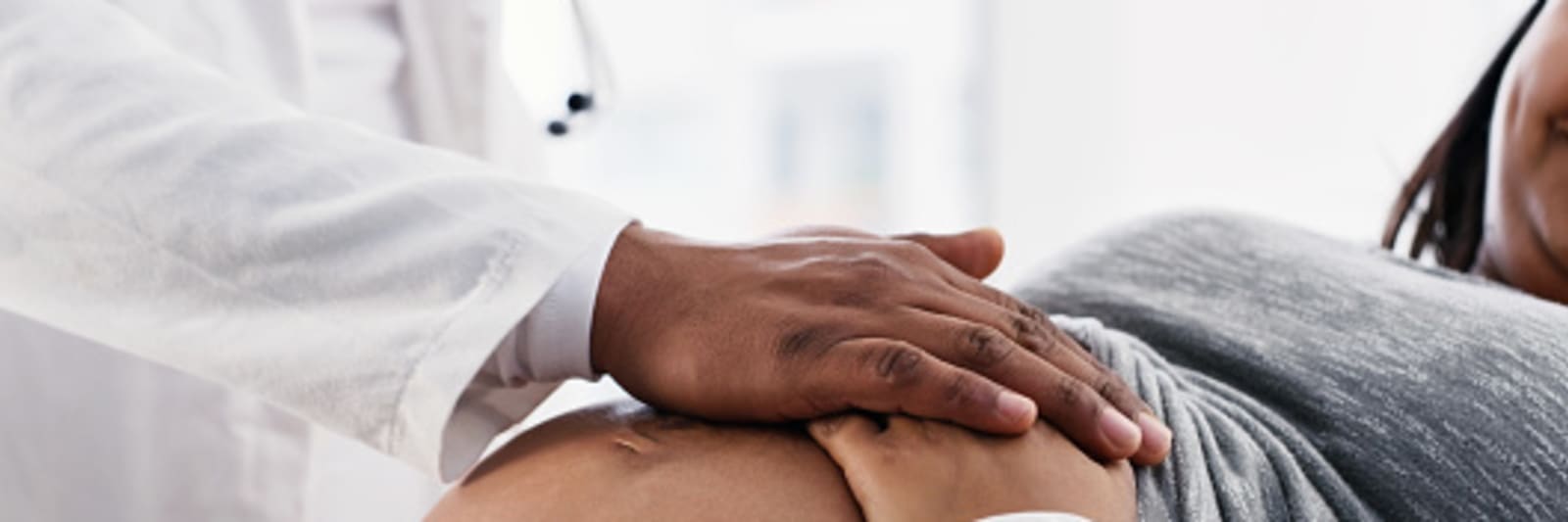 a doctor consoling and supporting a pregnant patient during her checkup at a clinic