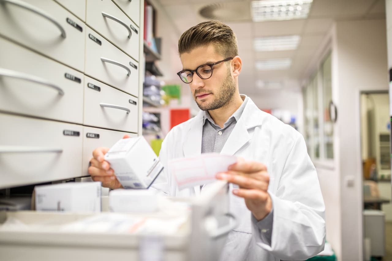 Male pharmacist checking medicines on rack