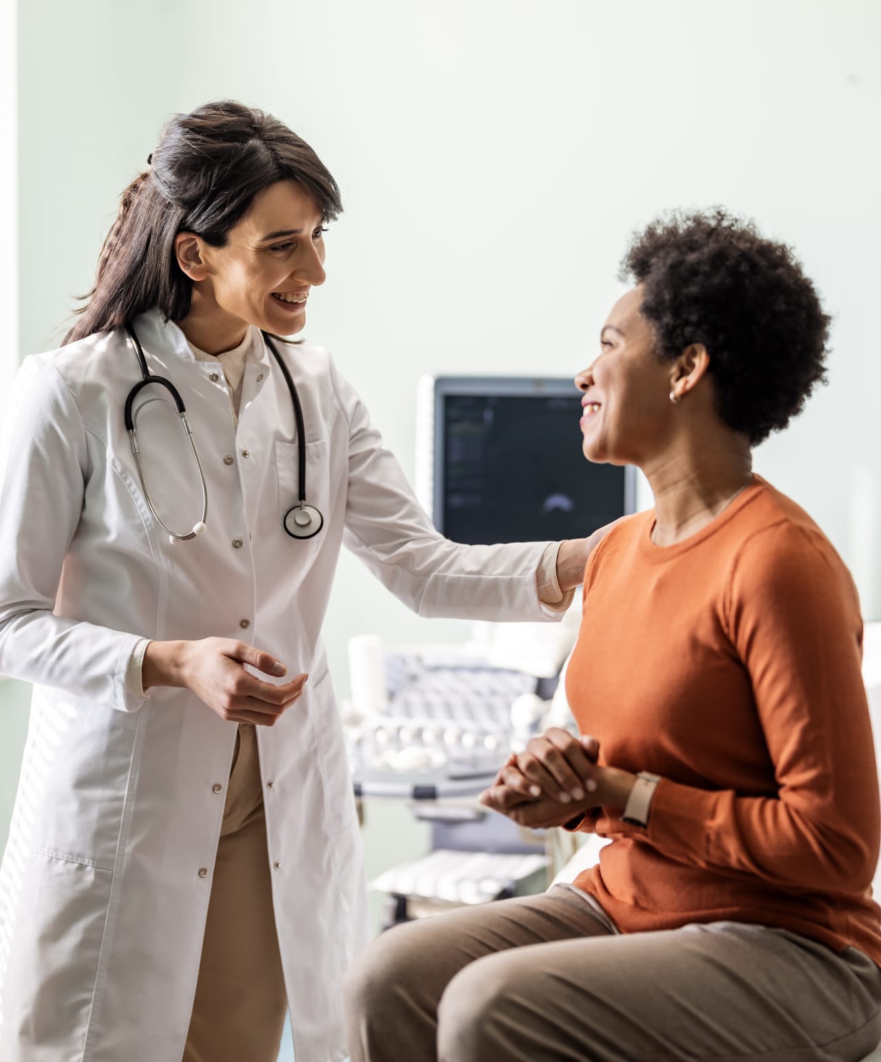 a female physician smiles at a female patient in a medical setting