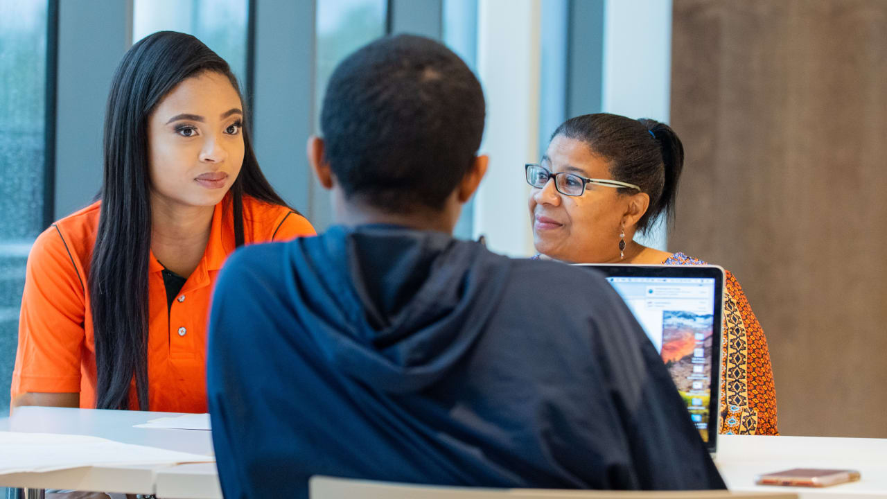 teenagers sit talking with a mentor at a table