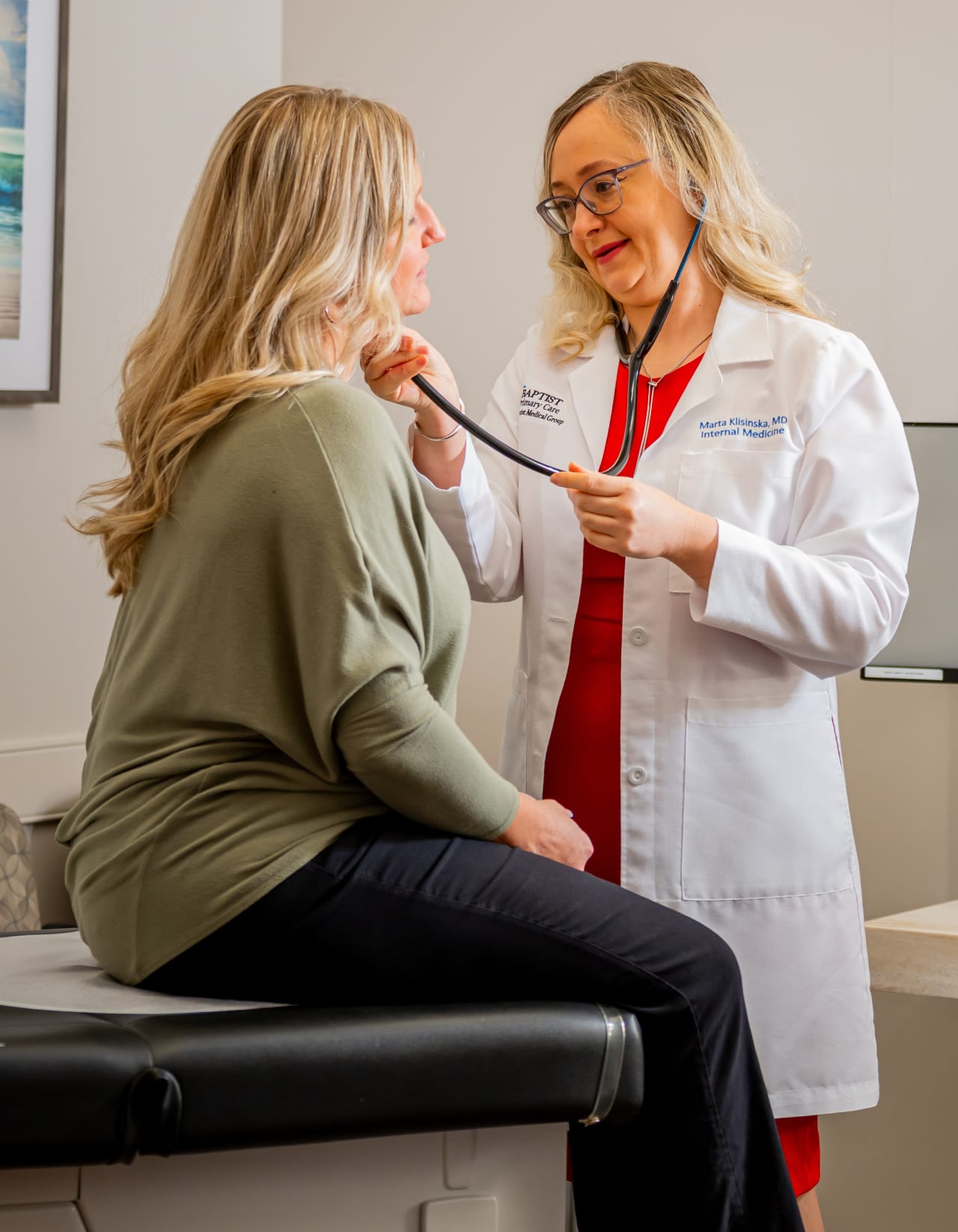 female physician examining a female patient with a stethoscope.