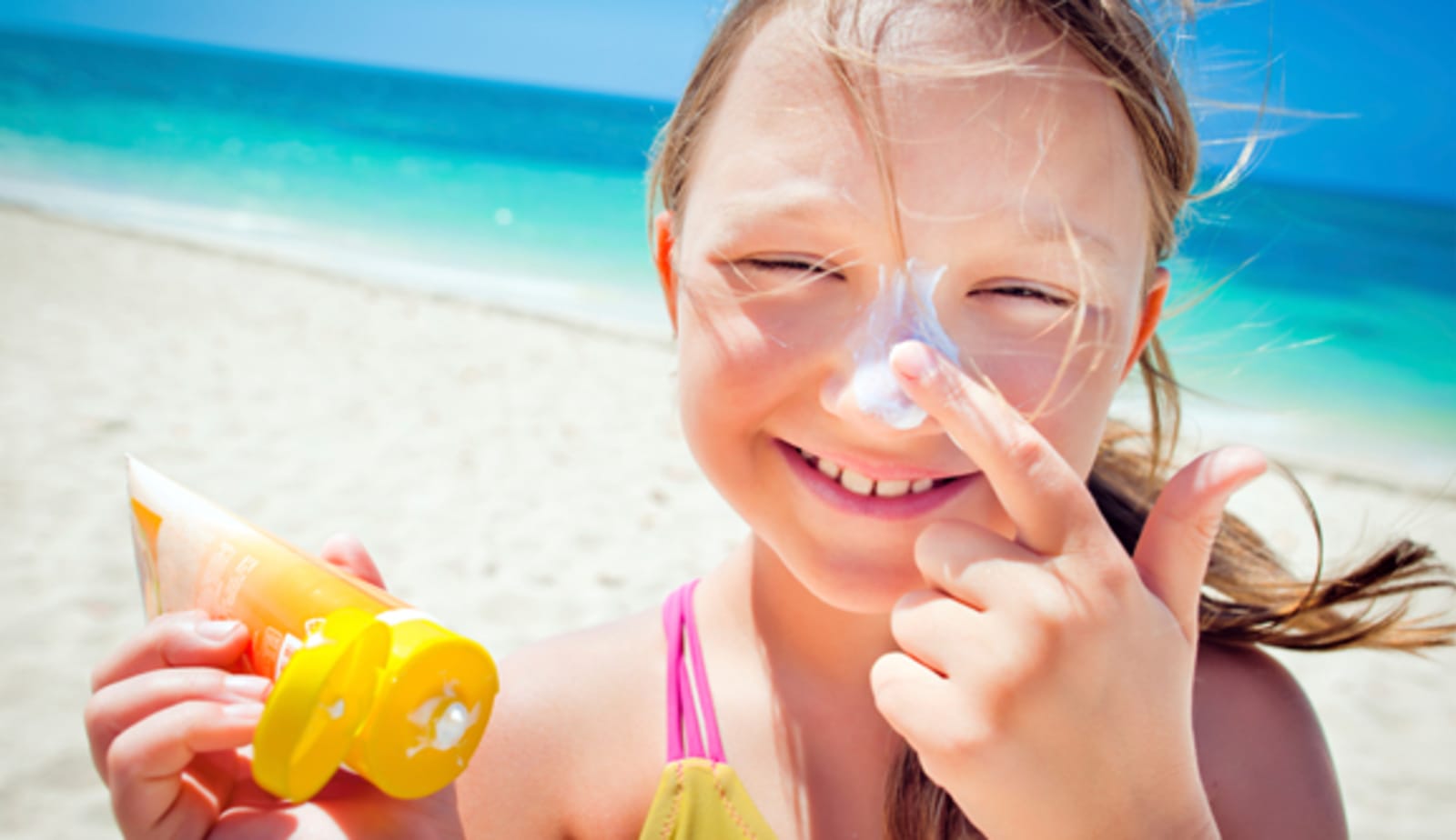 Little girl preventing sun damage with suncreen