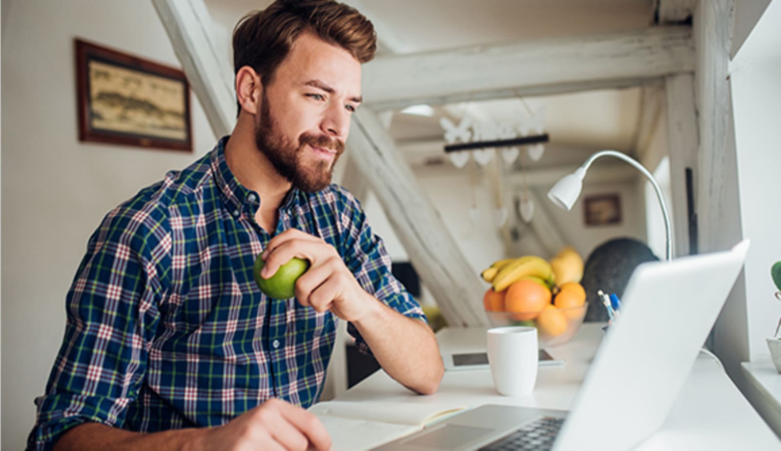 man eating apple at his laptop