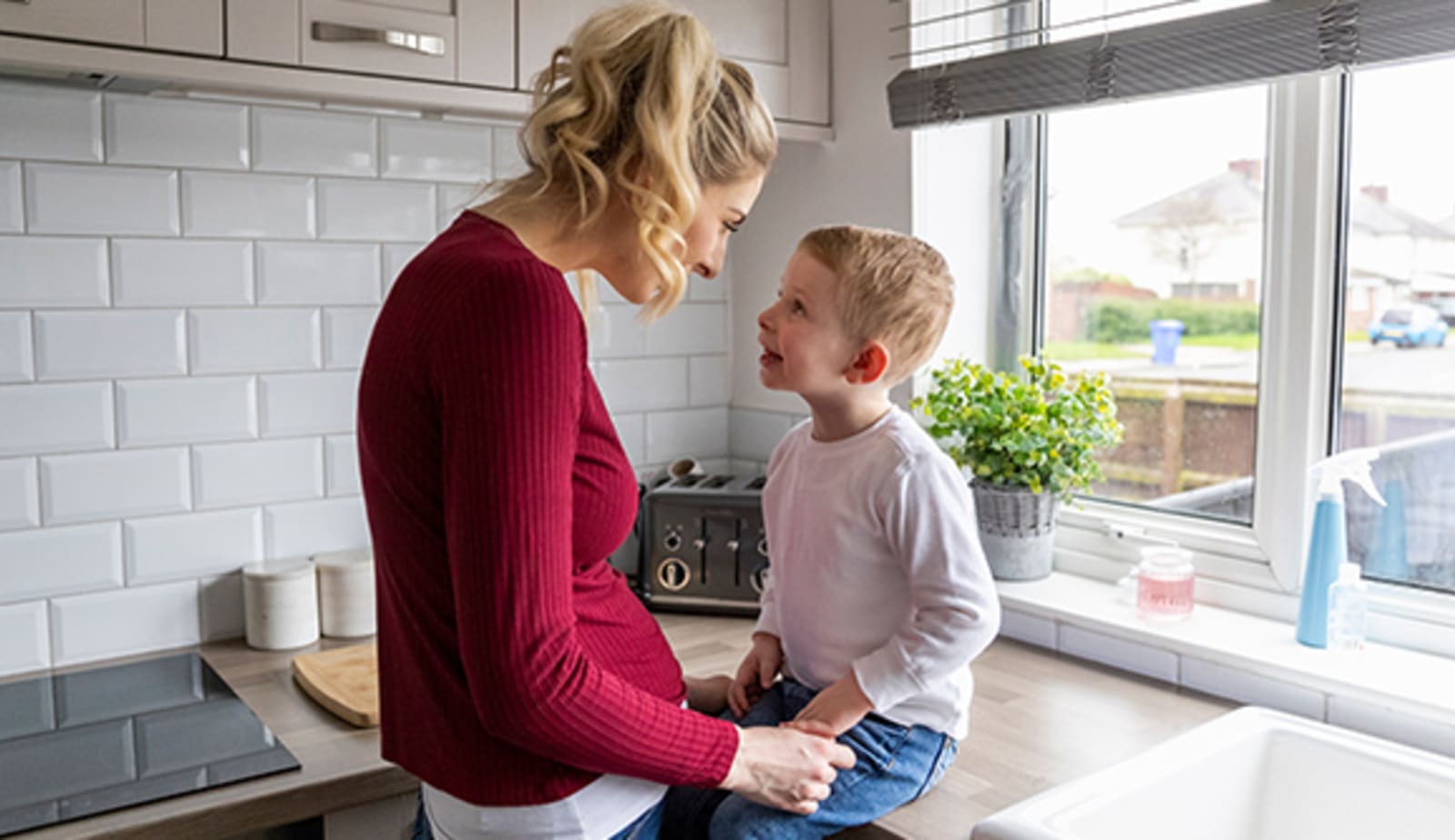 mom and her son sitting together in the kitchen by a bright window