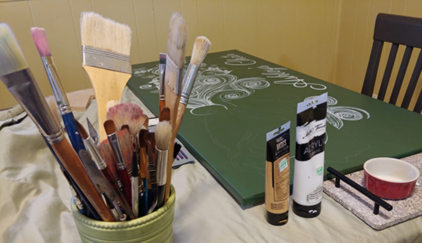 table covered in paint supplies including a canvas, paint and brushes