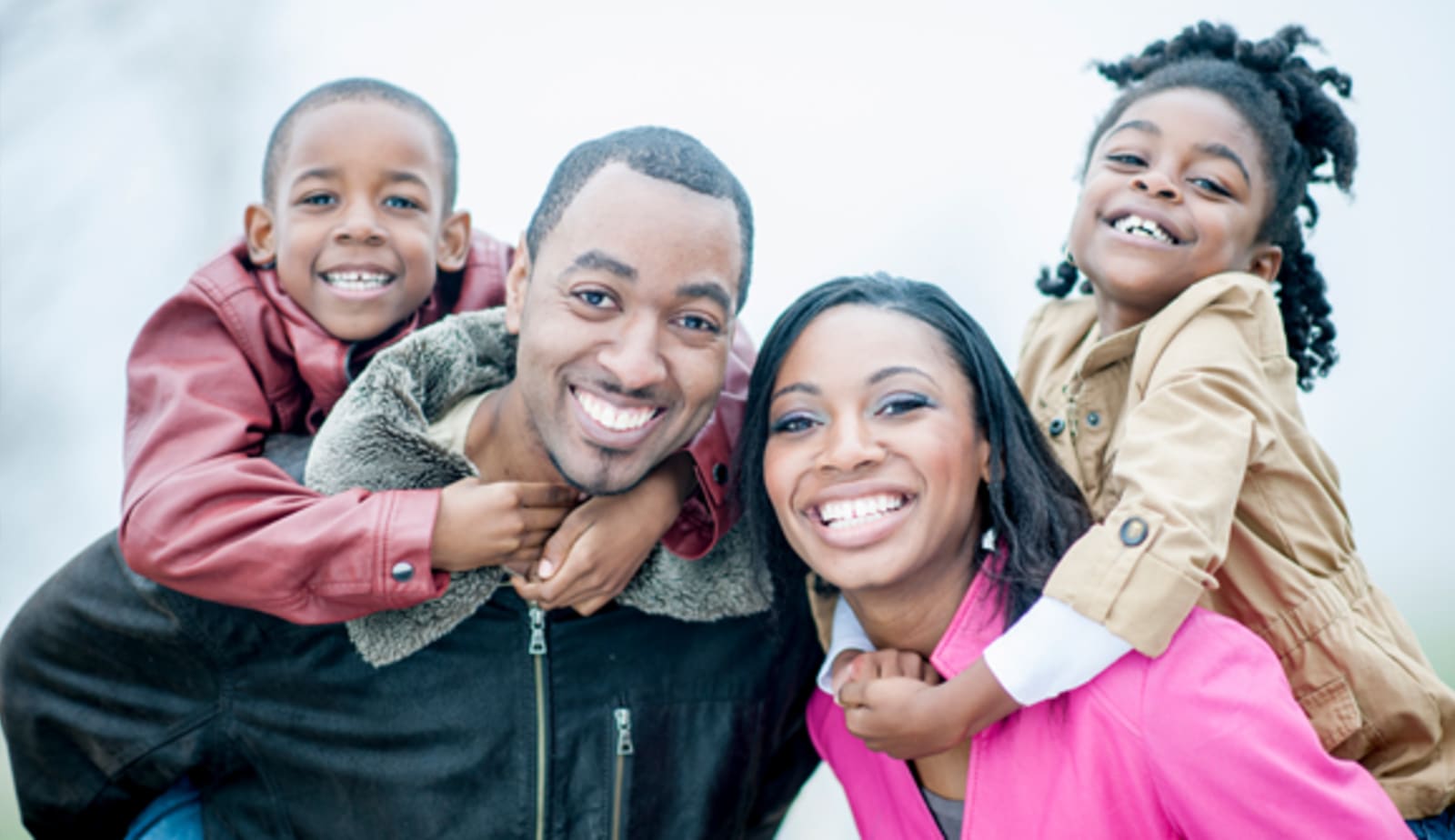 smiling family portrait of parents and two kids bundled up outside