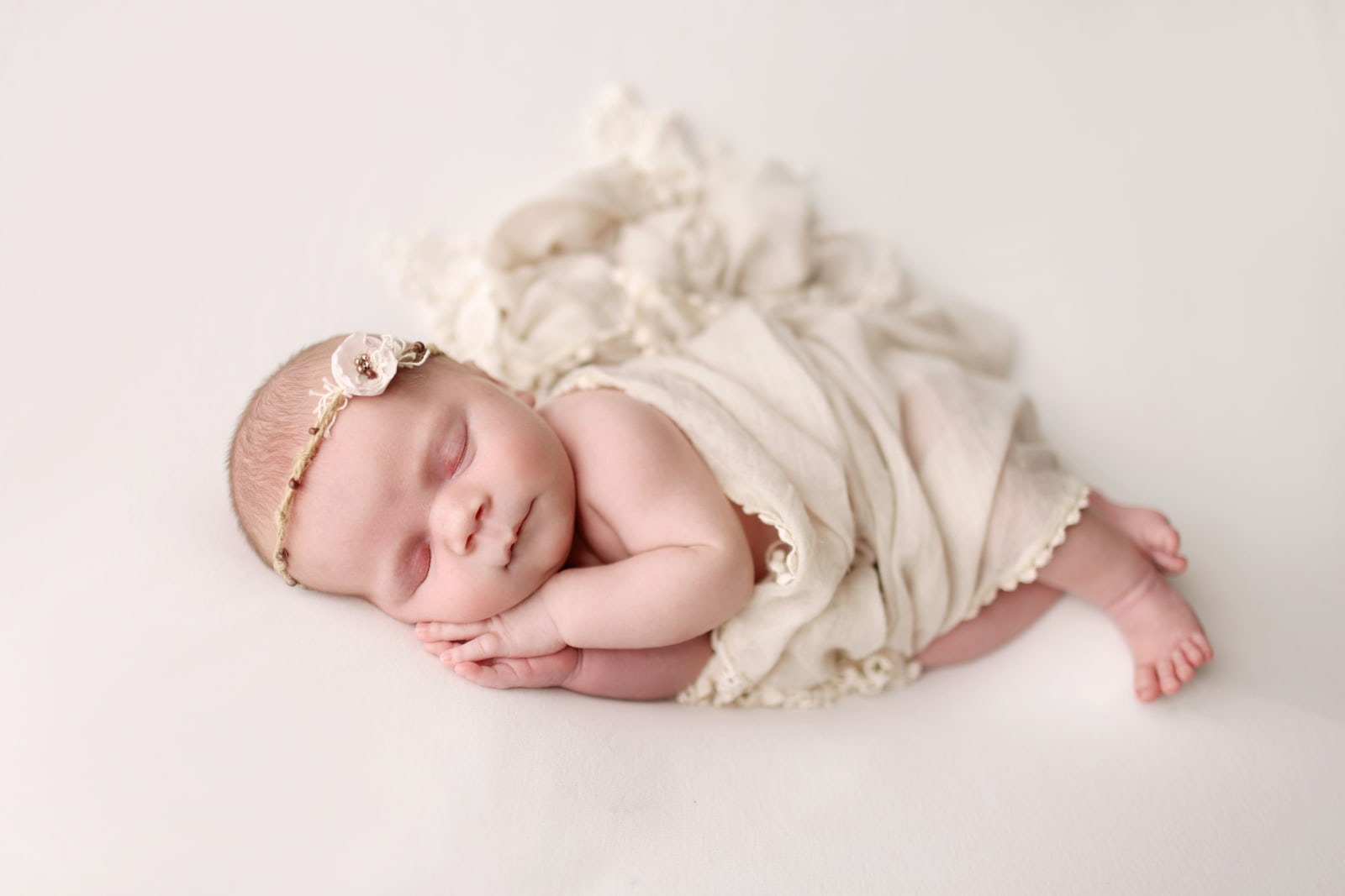 small baby sleeps peacefully while wrapped in a blanket and wearing a headband