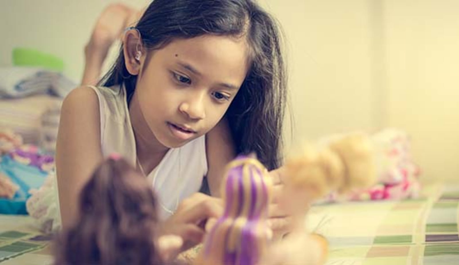 Girl with hearing aid playing with doll