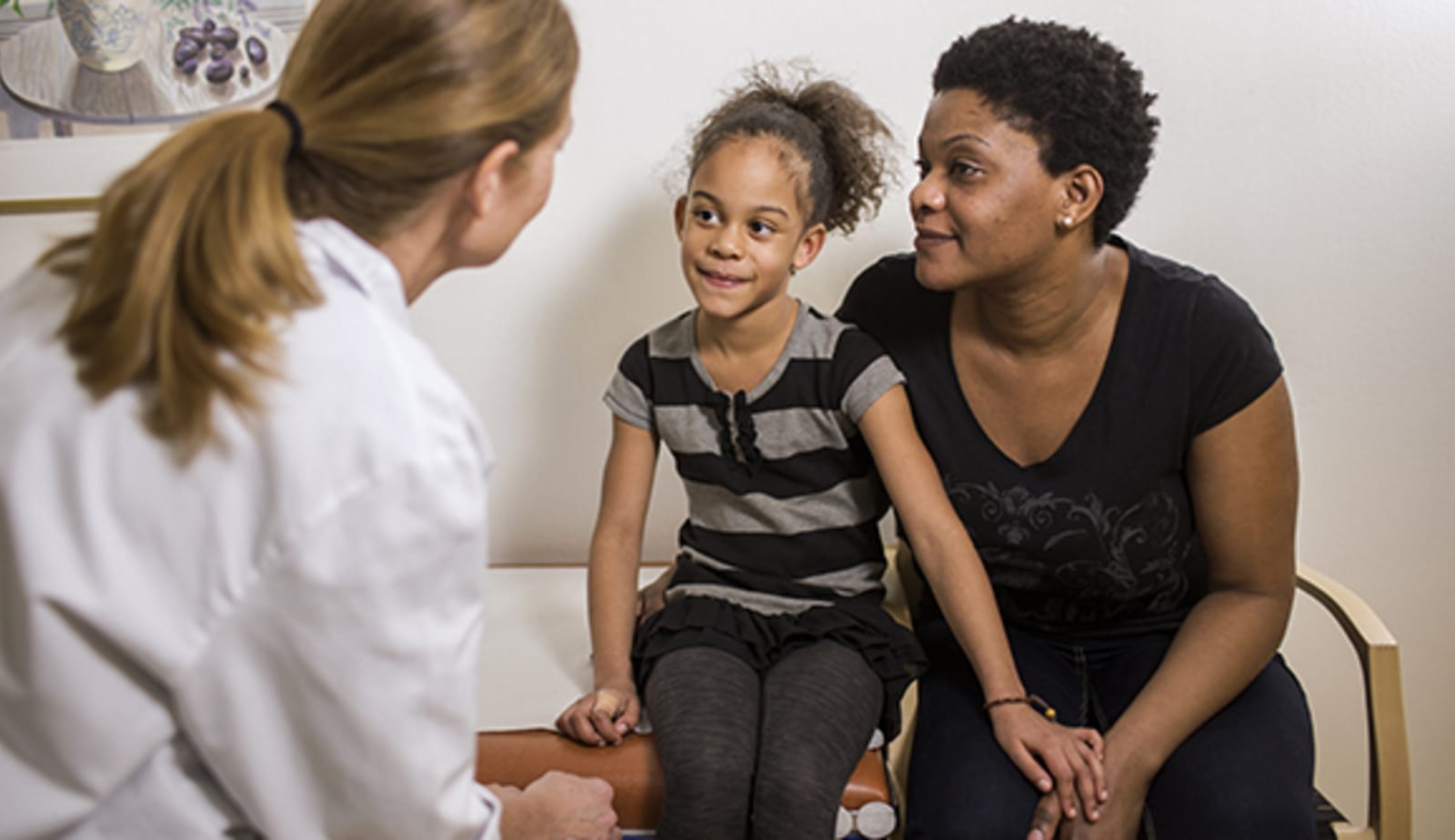 mom and elementary-aged daughter meet with female pediatrician for her annual checkup