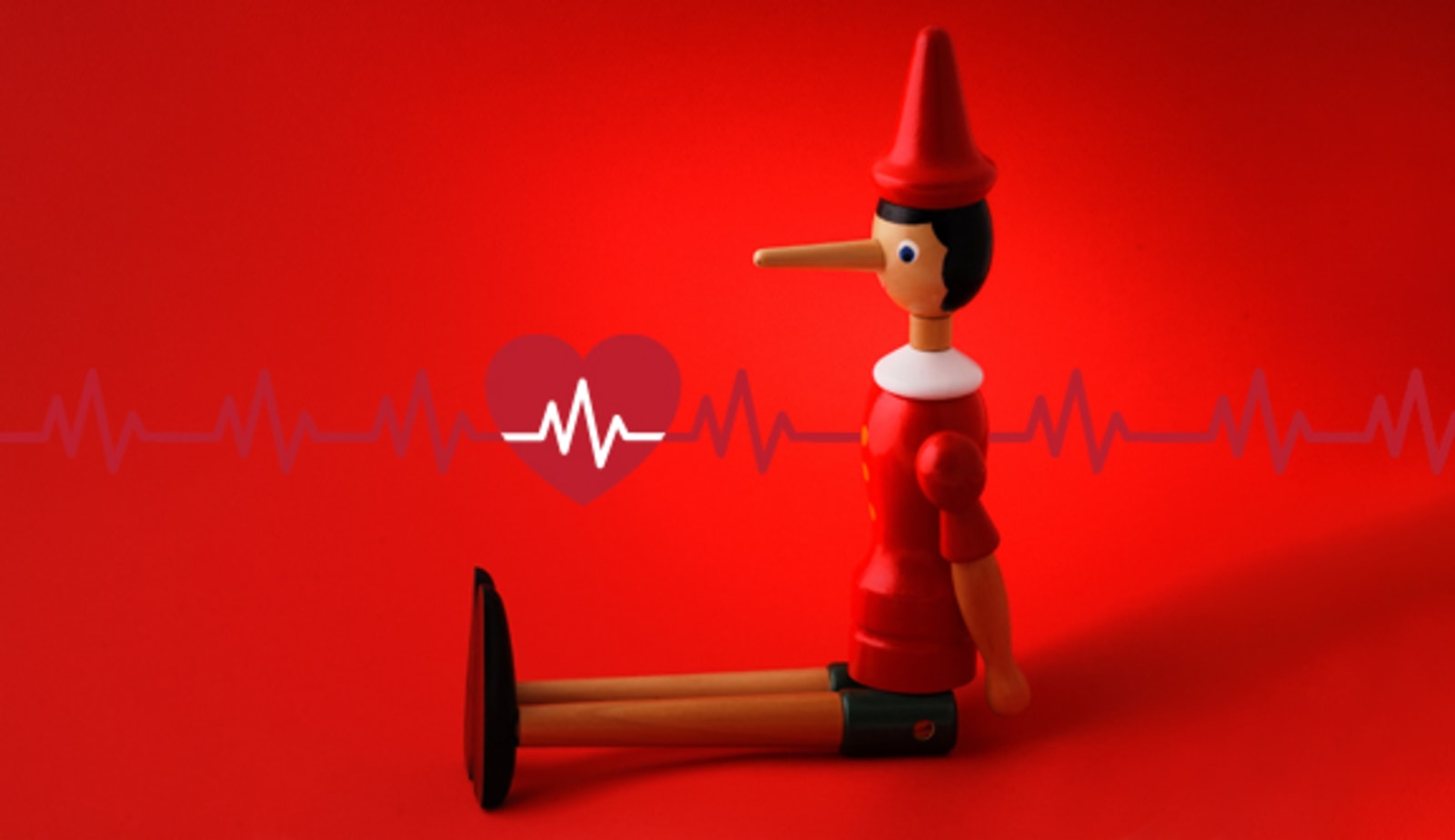 pinocchio doll sitting in front of a heart and heart rhythm, illustrating fibs about afib