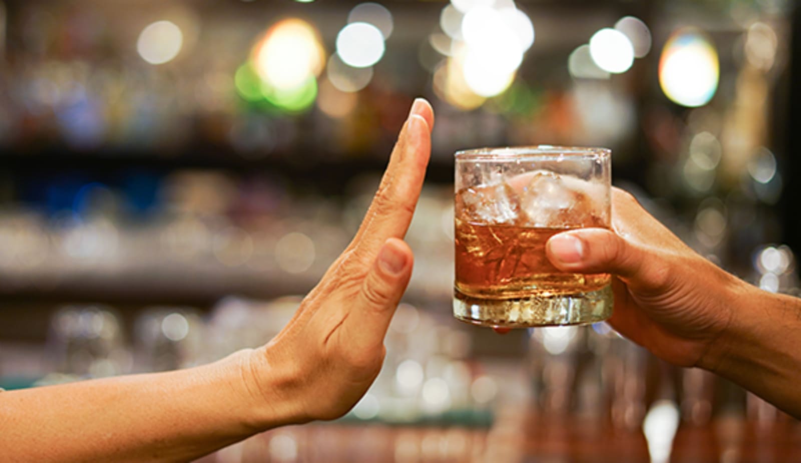 staying sober - a hand held up turning down an alcoholic beverage