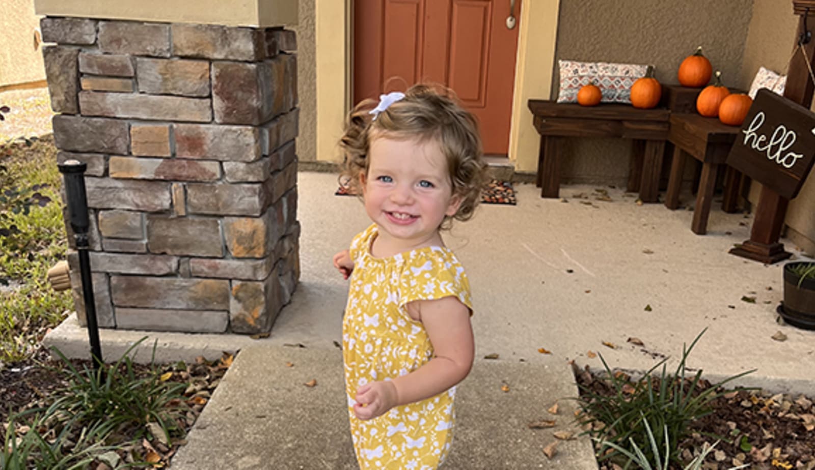 Little girl stands outside on a sidewalk smiling