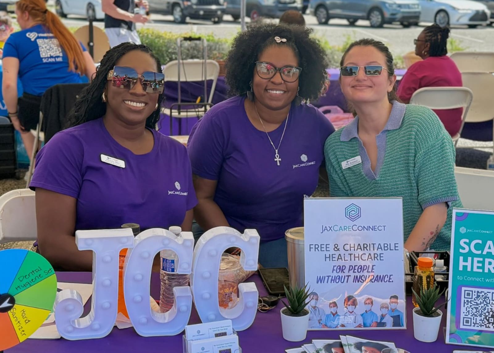 group of smiling women from JaxCareConnect sitting at a vendor booth together