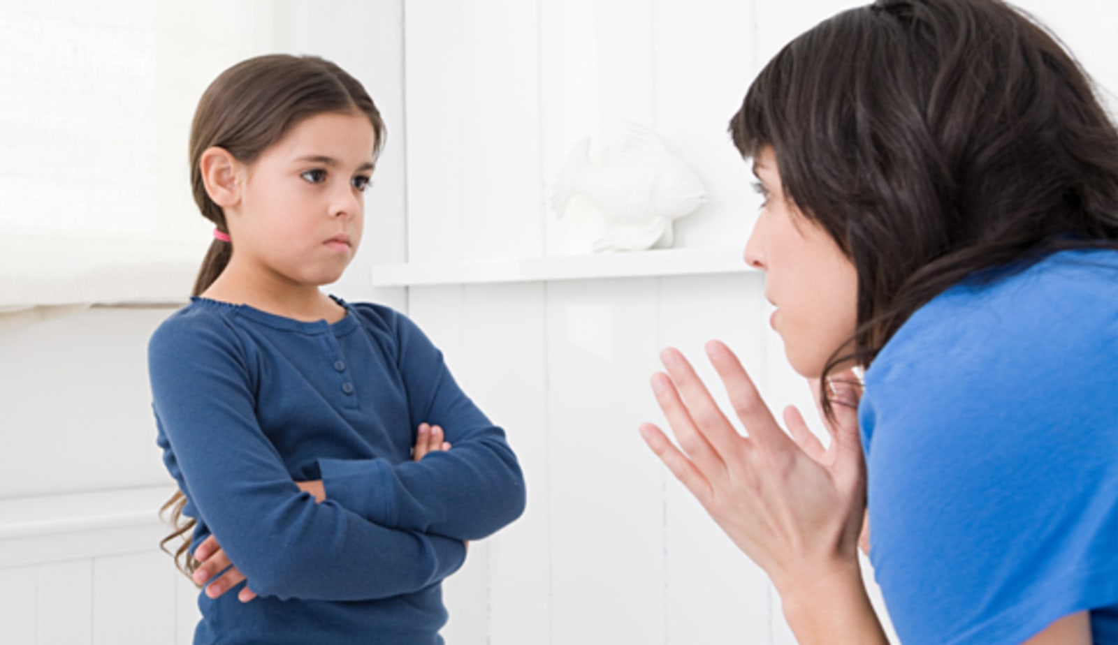 Child looking grumpy with arms crossed while parent tries to talk to them